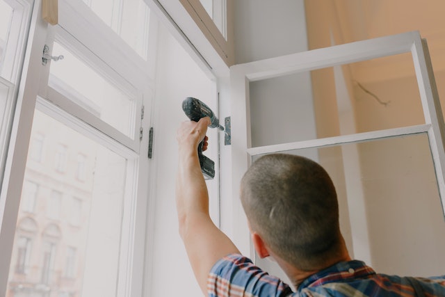 Person fixing the hinges of a white window