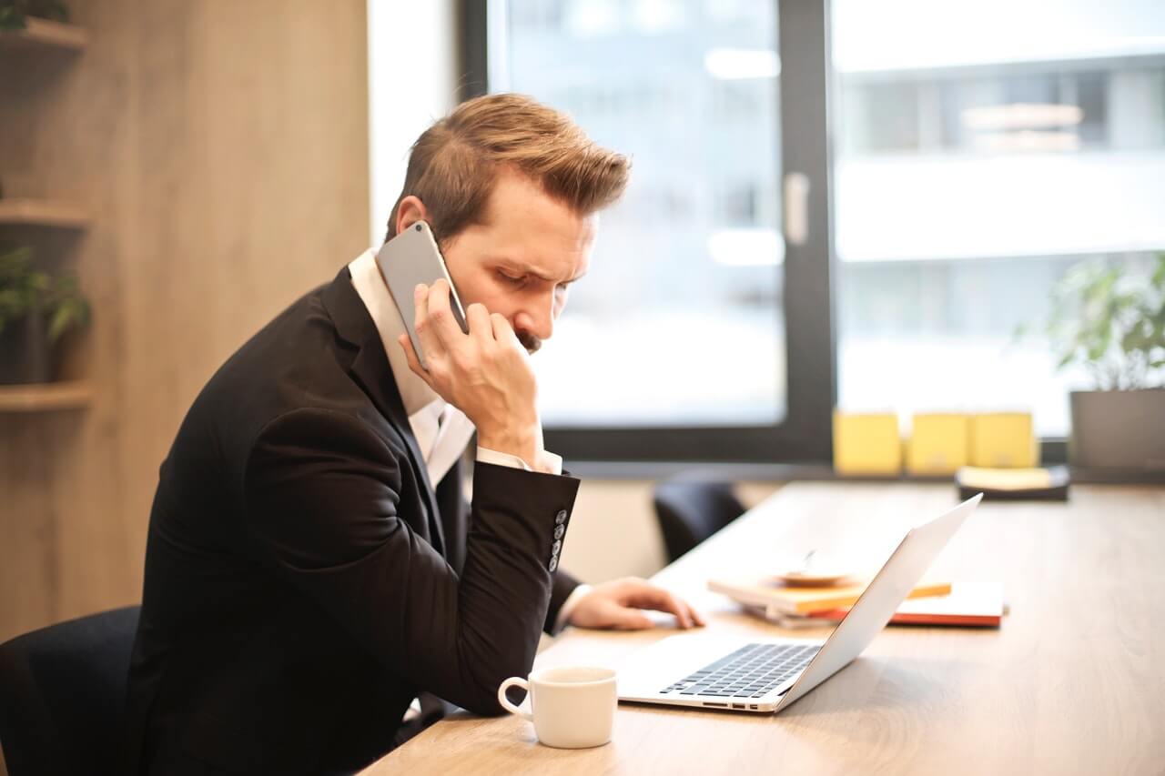 man on the phone in front of laptop