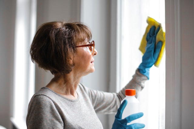 Older person with short brown hair wiping a window